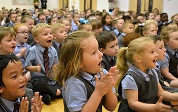 Kids at assembly sitting on the floor clapping